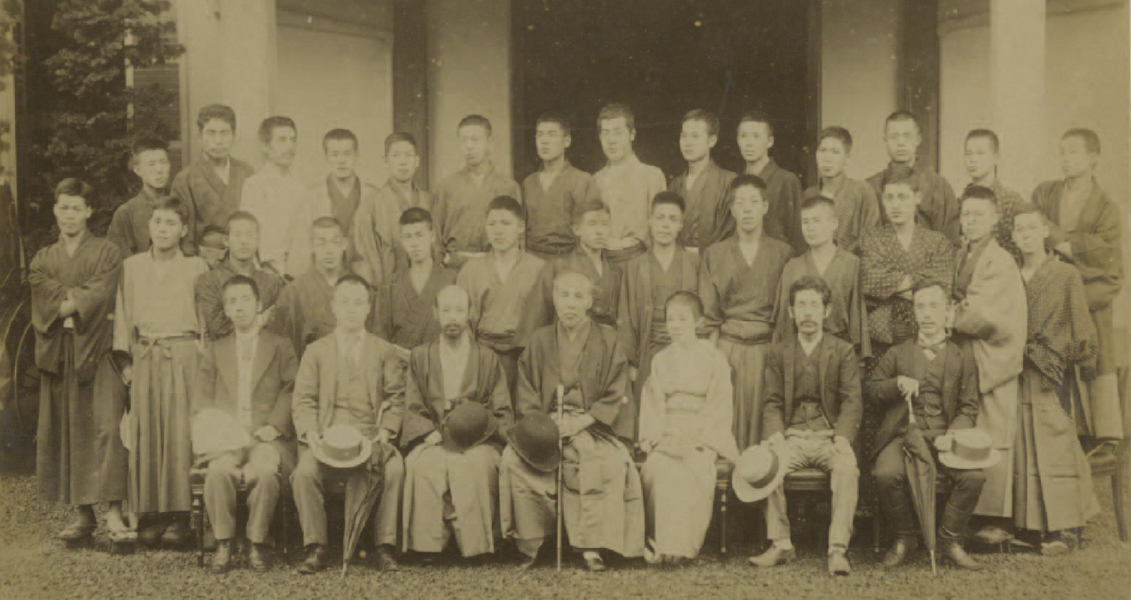 A photograph of a 1896 graduation cermony for the humanities department. Onishi is pictured in the front row, second from the right and Waseda founder Okuma Shigenobu is in the center.