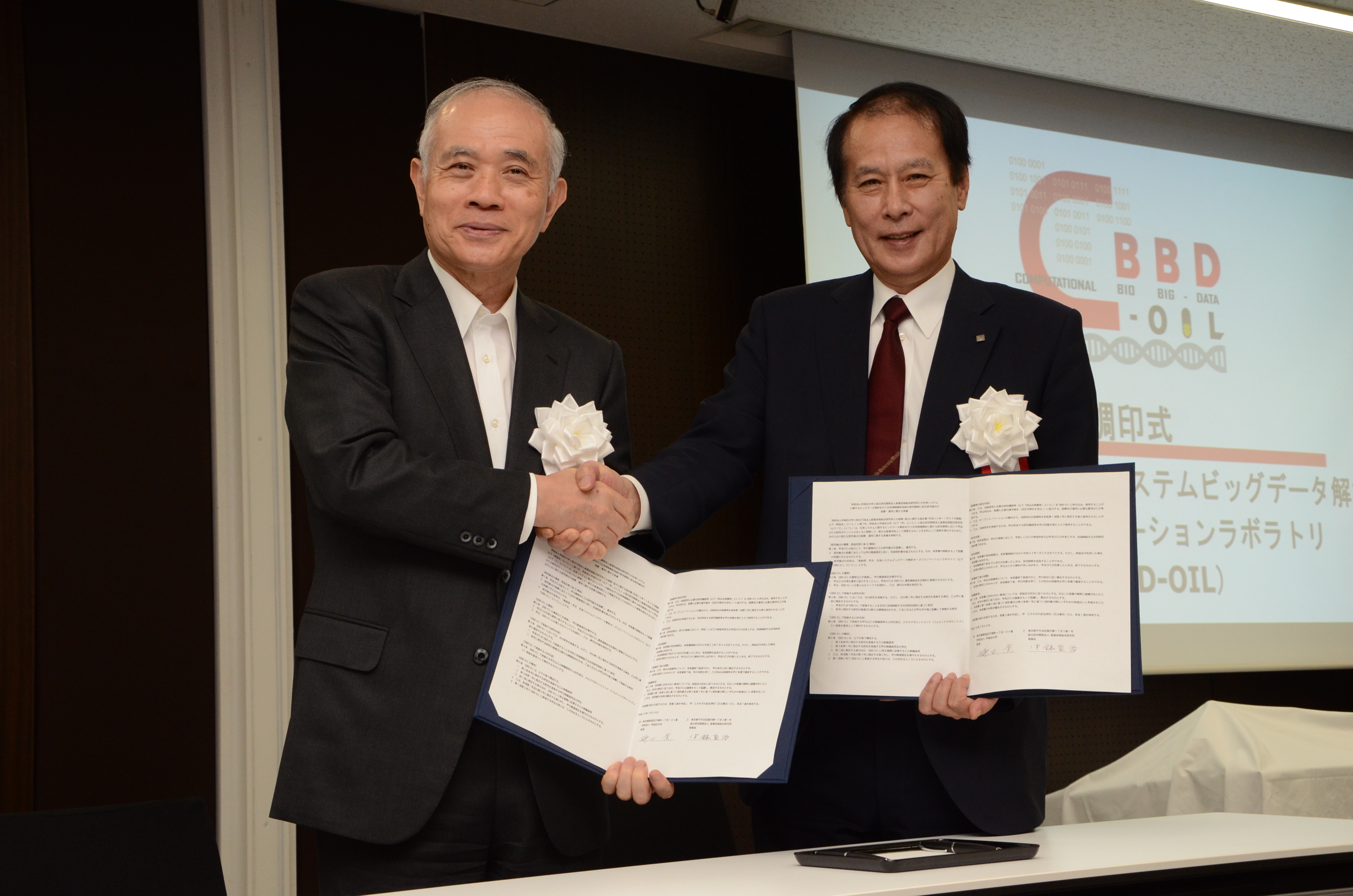 調印式後、握手を交わす産総研・中鉢良治理事(左)と早大・鎌田薫総長(右)