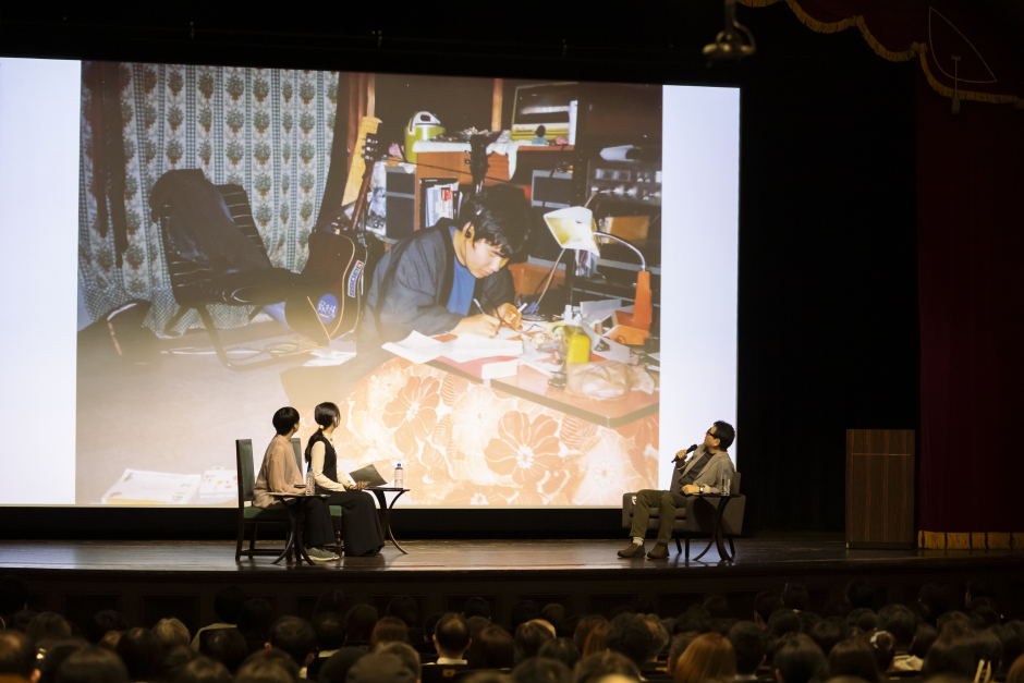 学生時代の写真を投影し、現在の文化との違いを説明する重松氏