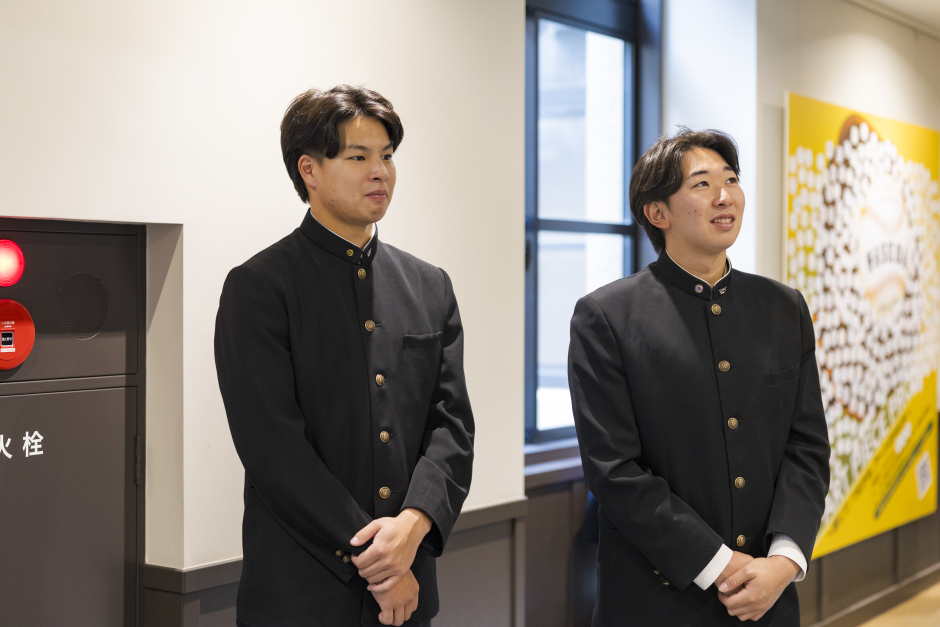 すべての野球部員が紹介されているボードを見て、感慨深い田和選手（左）、伊藤選手（右）