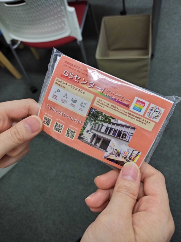 オレンジ色のパッケージにGSセンターの外観と内部の写真、GSセンターでできることのまとめ(個別相談、コミュニティ、図書利用、イベント)、各種ソーシャルメディアにアクセスできるQRコードが表示されている。GSセンターの名前とロゴも表示されている。