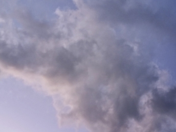 かなり薄い紺系の青色の空に、大きな雲が浮かんでいる様子が写っている。雲は綿菓子のようにやわらかく簡単にちぎれそうな見た目をしている。
