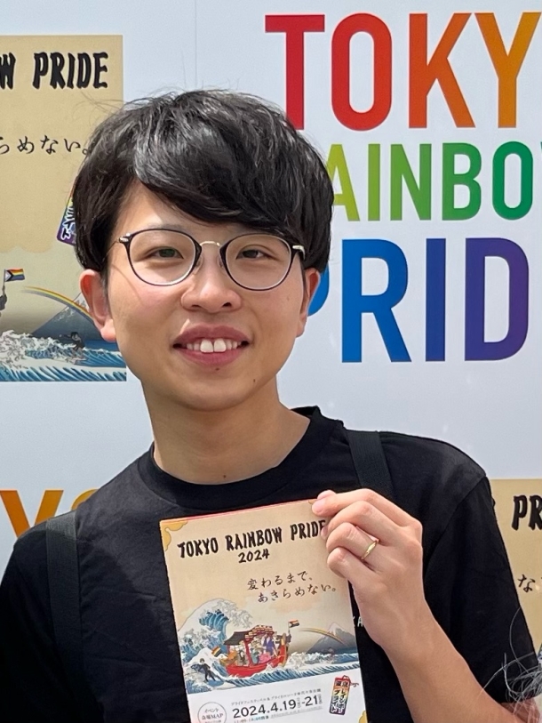 ともさんのプロフィール画像。メガネをかけて黒いTシャツを着たともさんが、イベントのフライヤーをカメラに向けて微笑んでいる。