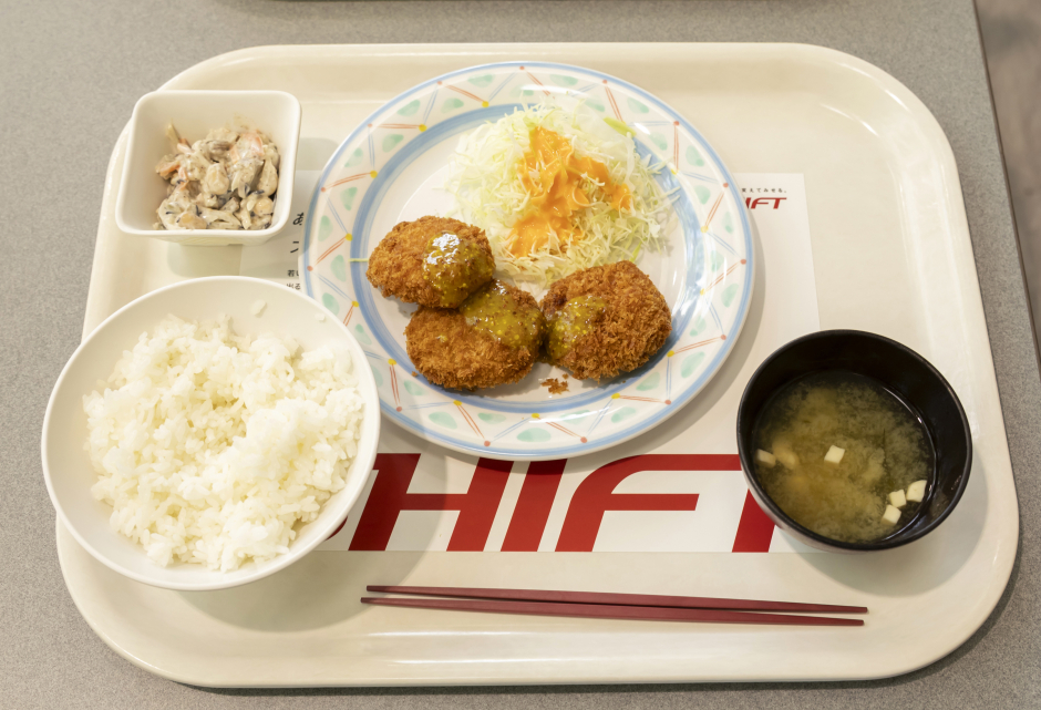 月曜日提供の定食(メイン:鮭チーズメンチ(ハニーマスタード)、小鉢:15品目のヘルシーサラダ、(中)ライス、味噌汁)