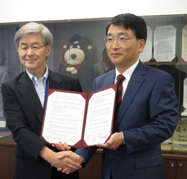 固く握手を交わす木村俊二教育長(左)、本杉秀穂学院長(右)