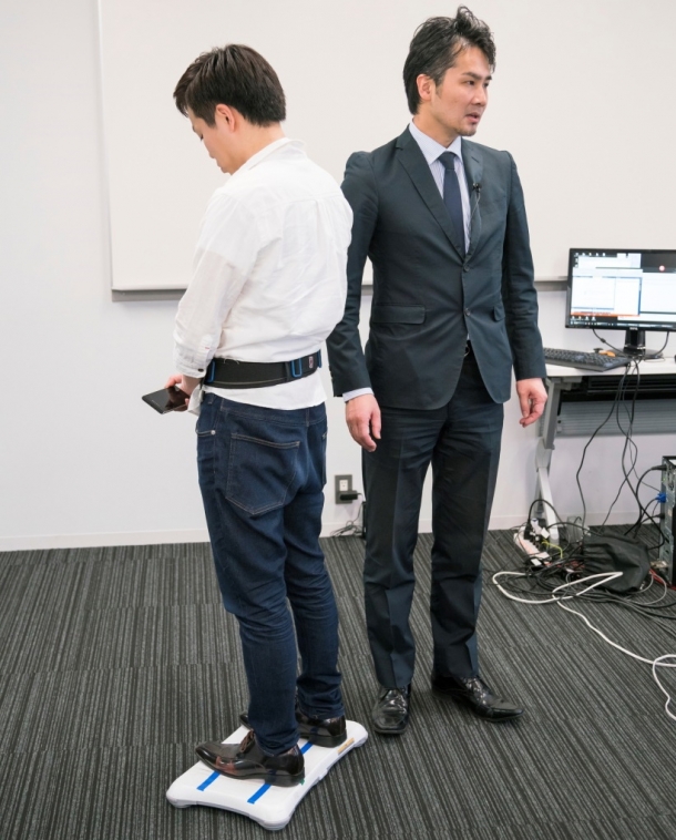 写真:バランス鍛錬ロボットテクノロジー。平衡感覚を鋭敏化するため腰に巻いたベルトへの振動で重心偏在を気付かせる。繰り返し訓練により、気づかないうちにバランス能力の向上が期待できる