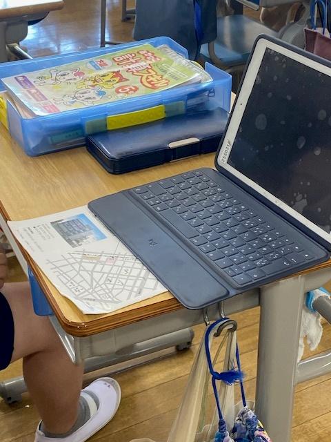 小学校低学年の机。机の規格は変わらないか?、学習の在り方か?変化したため、机上に乗り切れないほと?の教材・教科書か?ある。左側の青い箱はもう一つあり机の中に入れられている。.jpg